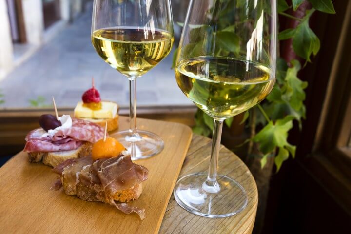 Cicchetti - italian tapas - with two wine glasses of white wine in venice - italy